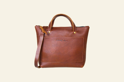 Brown leather tote bag with a strap on a white background