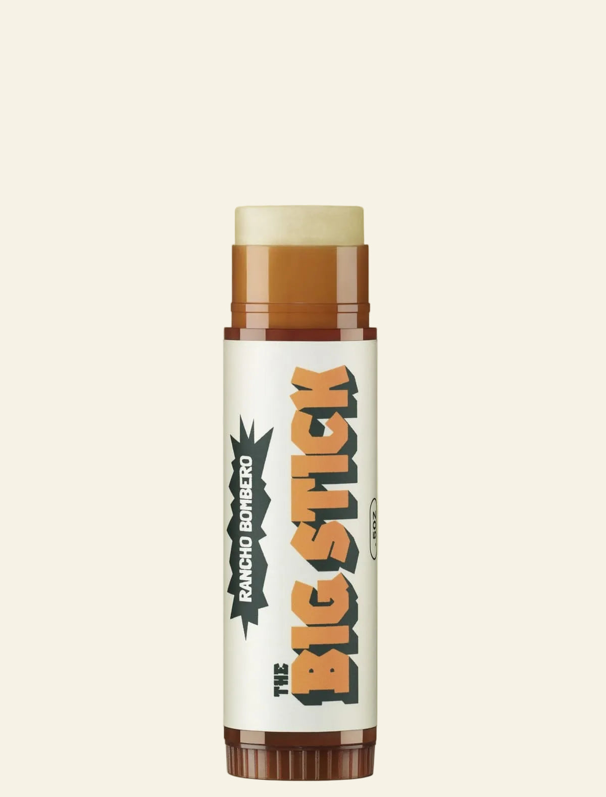 A single stick-style lip balm or cosmetic stick centered on a plain warm beige background. The product has a white label with large orange and black text reading &