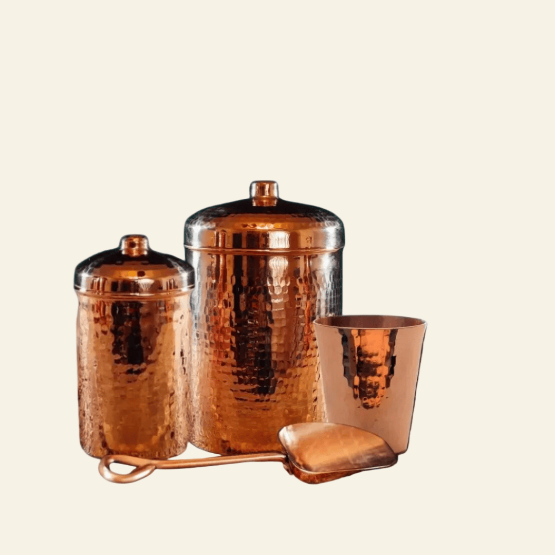 Set of three copper canisters with lids on a light beige background