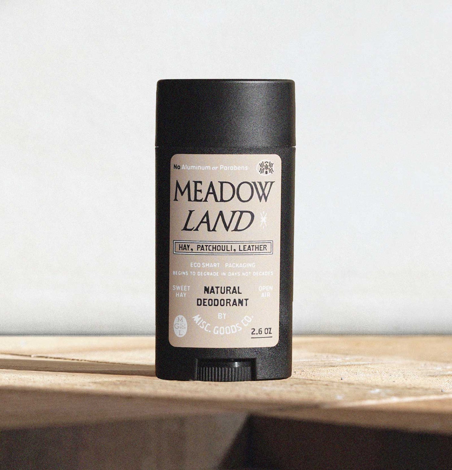 Meadow Land deodorant stick on a wooden surface with a light gray background