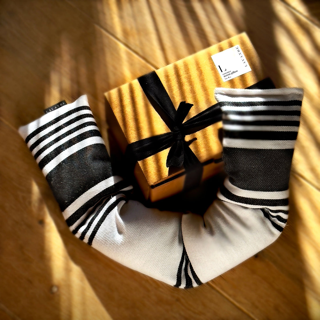 Gift box with black ribbon and two black and white striped socks on a wooden surface