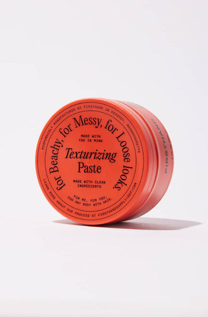 Red container of texturizing paste with black text on a white background