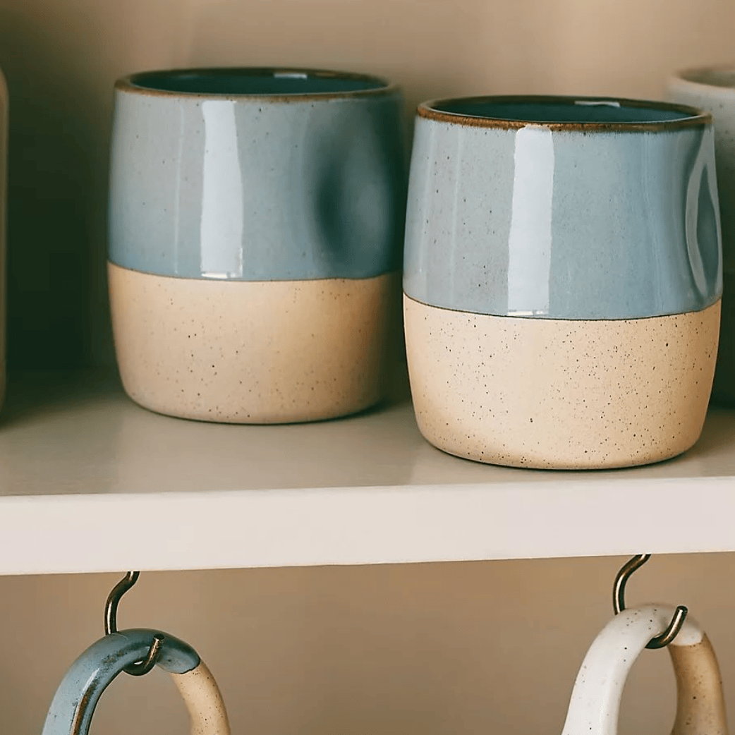 Two ceramic jars with blue and beige finish on a shelf.
