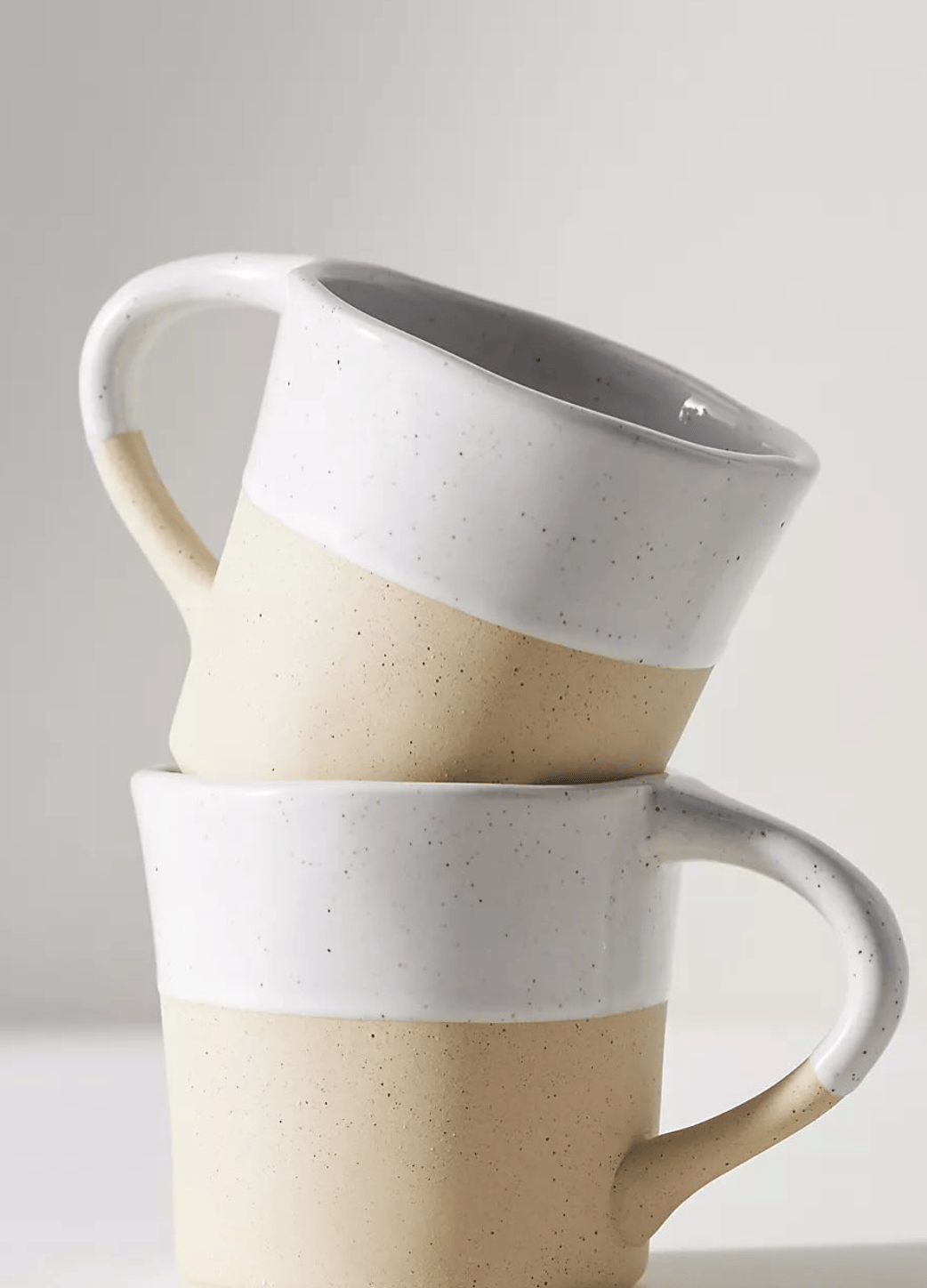 Two ceramic mugs stacked on a light gray background