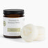 An amber glass jar candle with a black lid and a white label reading &