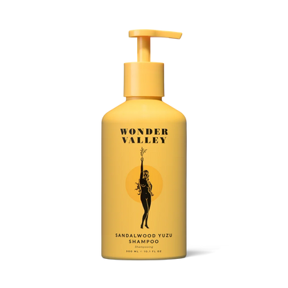 Wonder Valley Sandalwood Yuzu Shampoo in a yellow pump bottle with a black graphic of a woman holding a yuzu and the brand name &