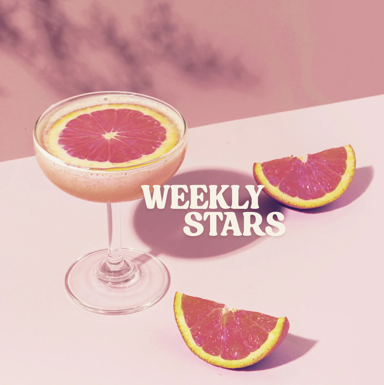 Glass of drink with slices of fruit on a pink background with words Weekly Stars