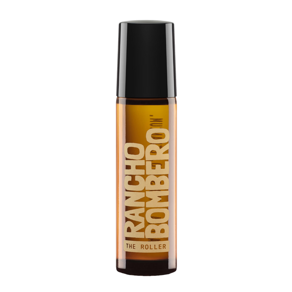A bottle of Rancho Bombero nm' The Roller hair product, featuring an amber brown bottle, a black cap, and beige lettering on the front label, set against a plain white background.