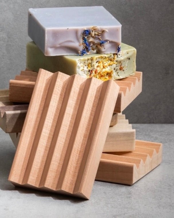 Wooden soap dish with three bars of soap on a gray background