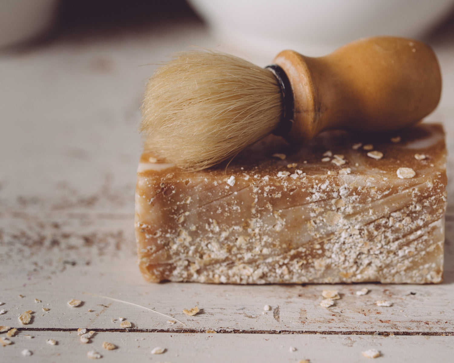 Bar of soap with a brush on top on a wooden surface