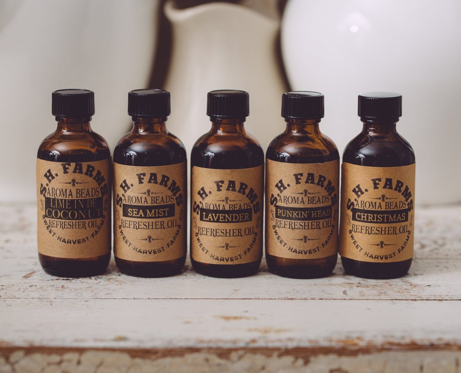 Five bottles of H. Farm Aroma Beads on a rustic surface with a blurred background.
