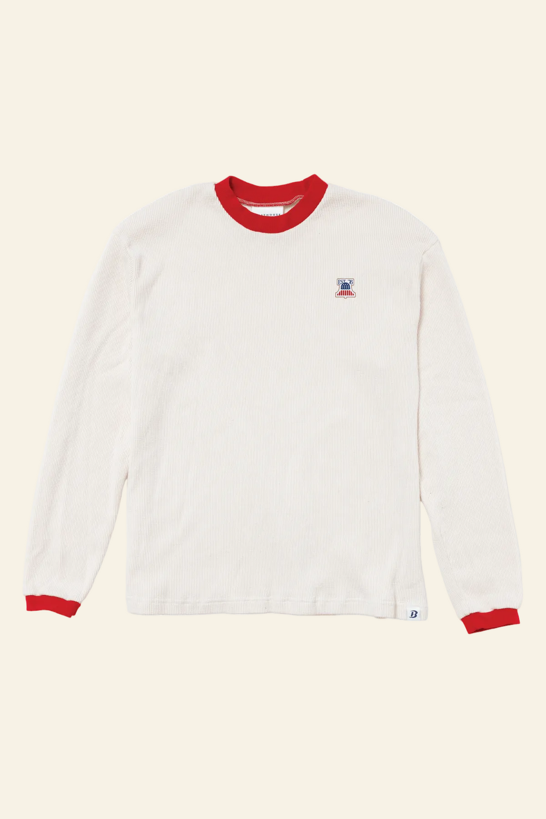 An off-white long-sleeve t-shirt with red ribbed collar and cuffs, featuring a small embroidered logo on the left chest and a small white tag near the bottom hem, displayed on a clean white background.