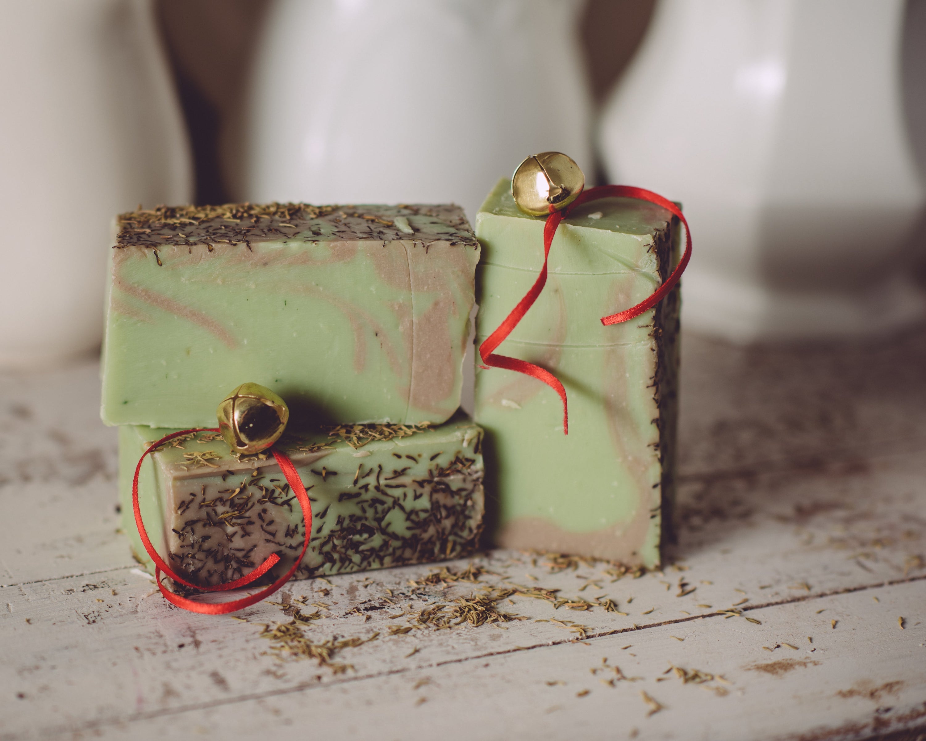 Three green soap bars with red ribbons on a wooden surface