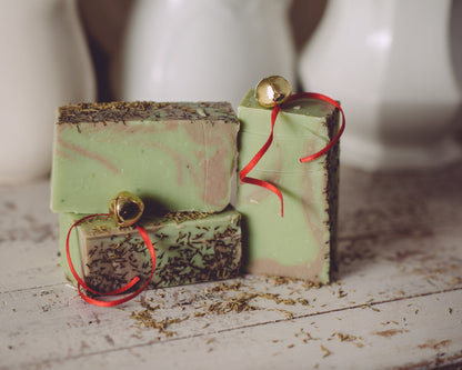 Three green soap bars with red ribbons on a wooden surface