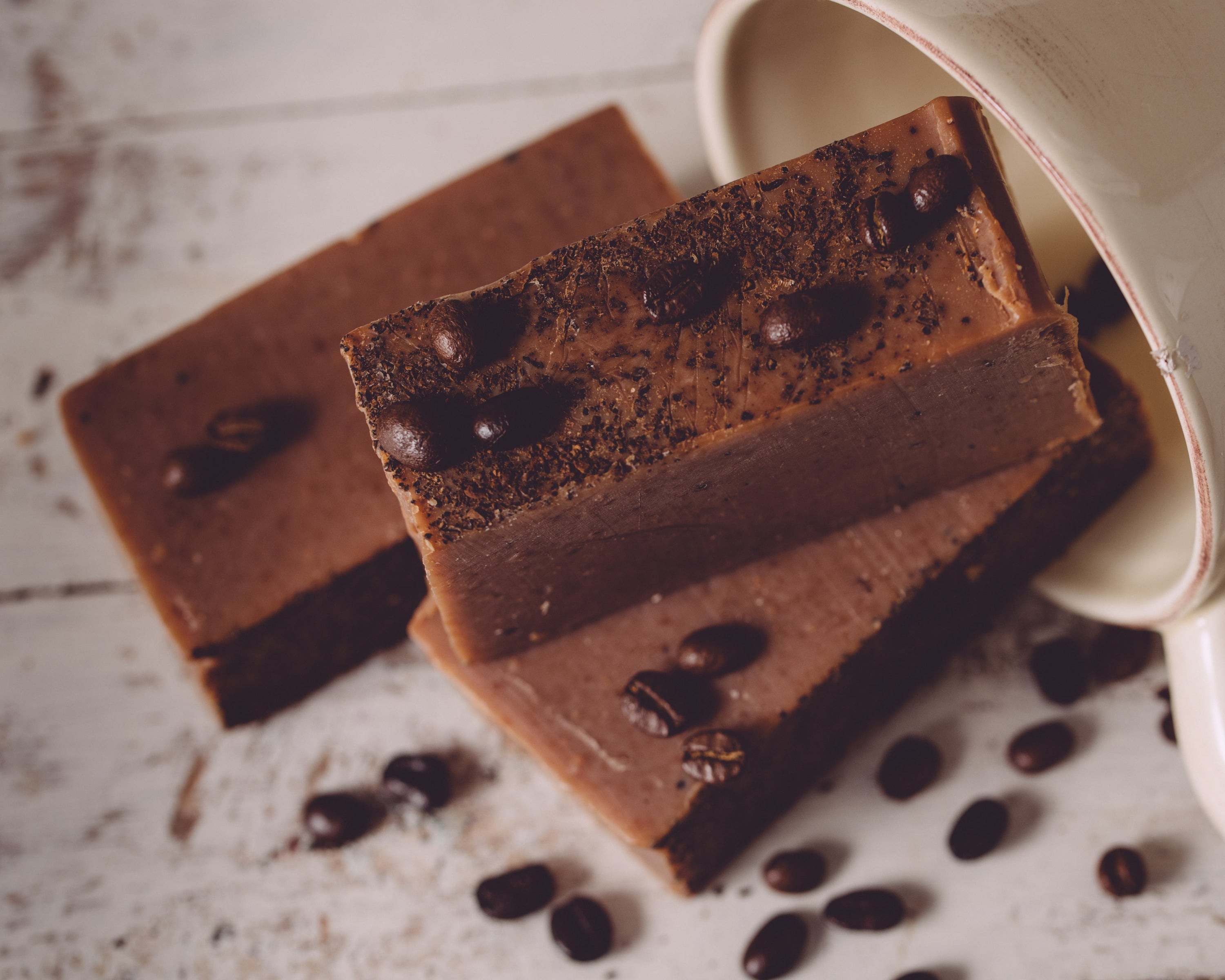 Chocolate soap bars with coffee beans on a textured surface