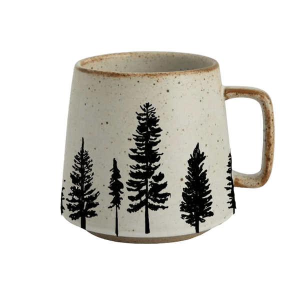 A speckled cream ceramic mug with a black pine tree silhouette pattern, set against a solid green background.