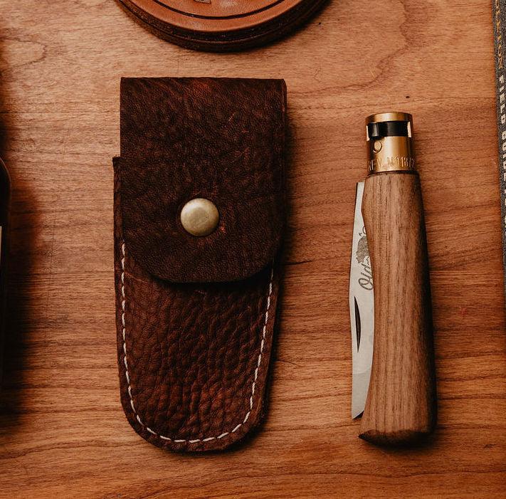 Wooden knife with leather sheath on a wooden surface