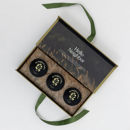 Three black containers with gold labels in a decorative box labeled &