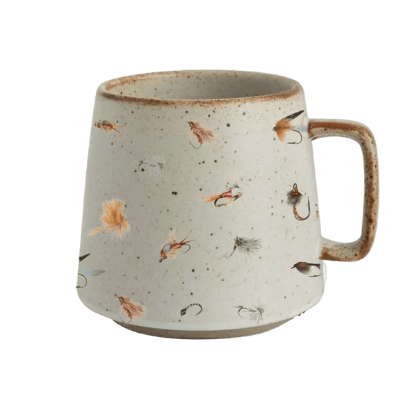 A speckled ceramic mug with a handle, decorated with small fly fishing hooks and feathers in earthy brown and beige tones, shown against a solid green background.