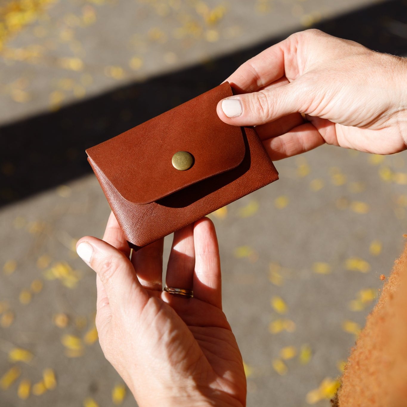 Brown leather wallet held by hands with a blurred background