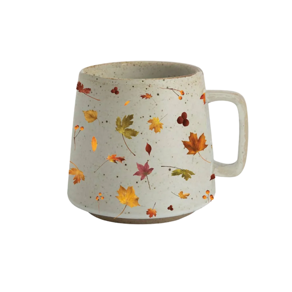 A speckled off-white ceramic mug with a handle, decorated with a pattern of colorful autumn leaves in orange, yellow, green, and red.
