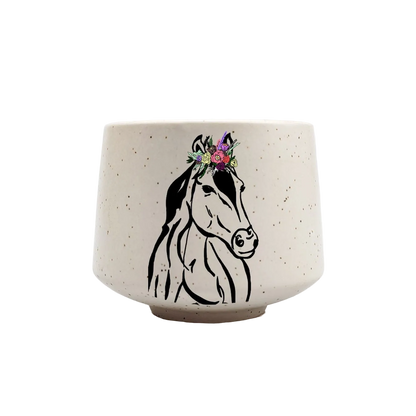 A speckled cream-colored ceramic cup featuring a black line-art illustration of a horse&