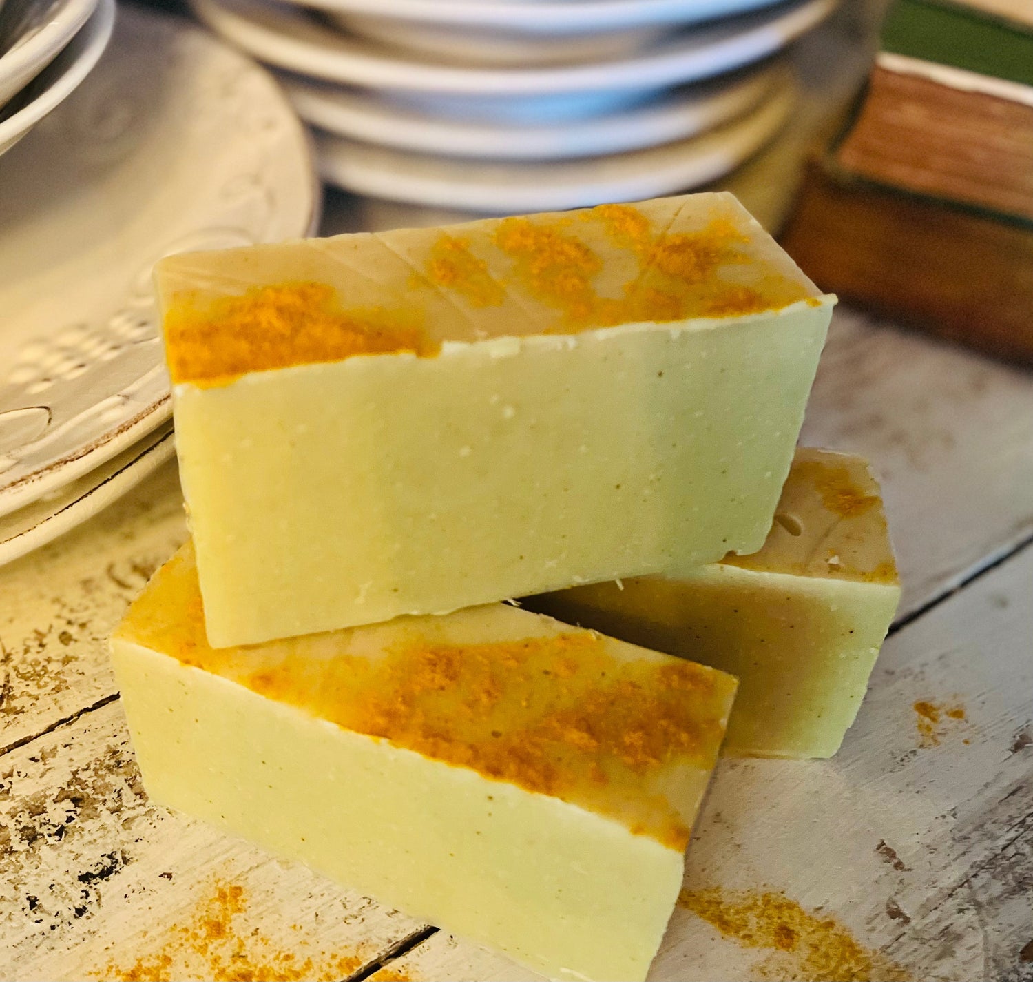 Three bars of soap with orange specks stacked on a wooden surface