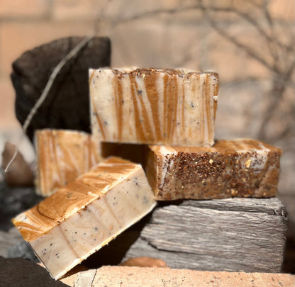 Stack of soap bars with brown and beige marbled pattern on a rustic wooden surface.
