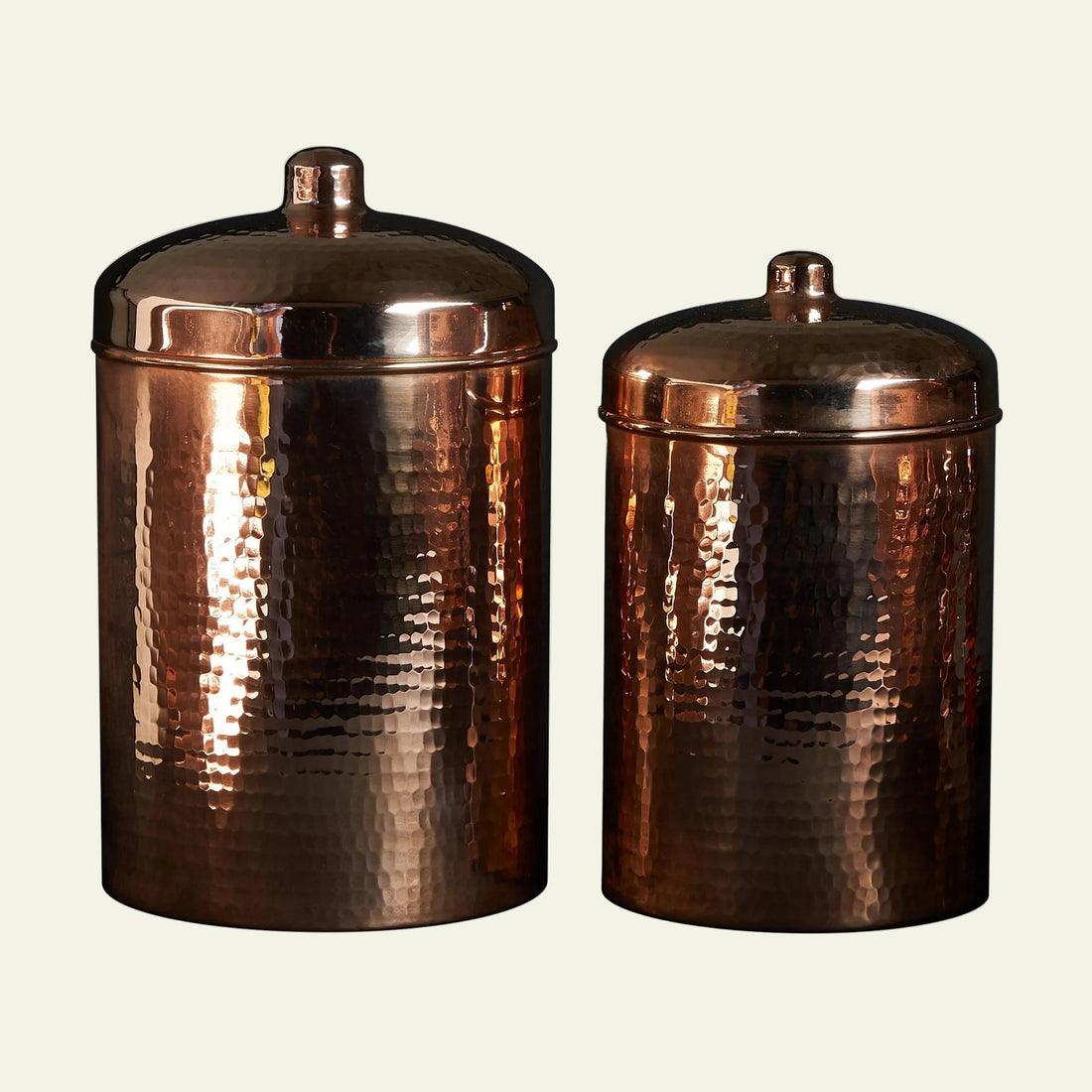 Two copper canisters with lids on a white background