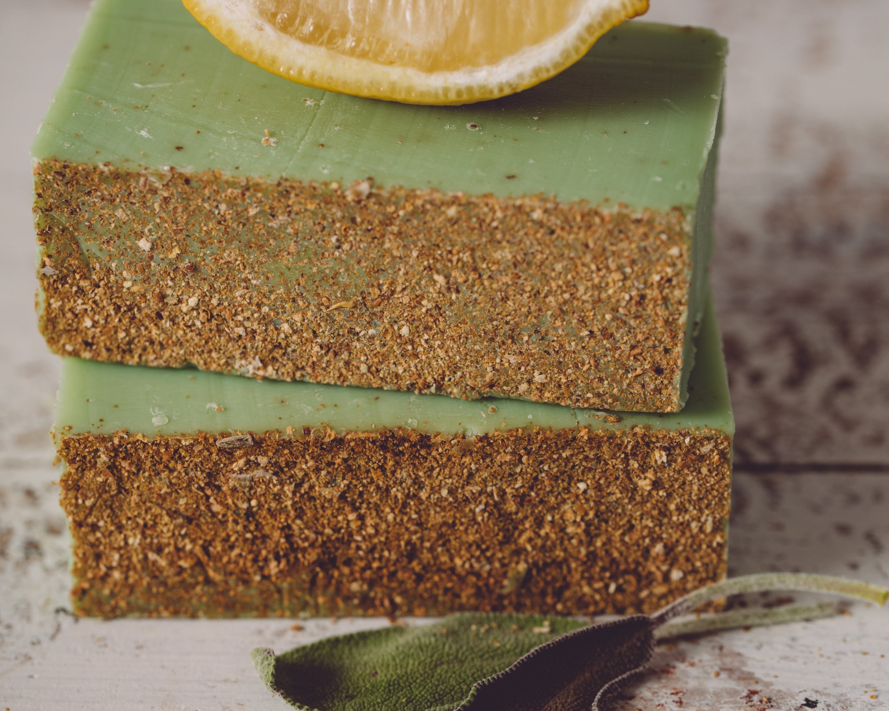 Three layered green and brown bar of soap with a lemon wedge on top.