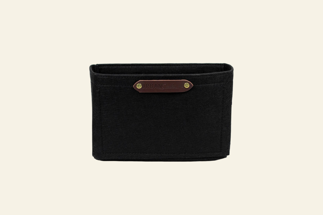 Black woven basket with a brown leather strap on a white background