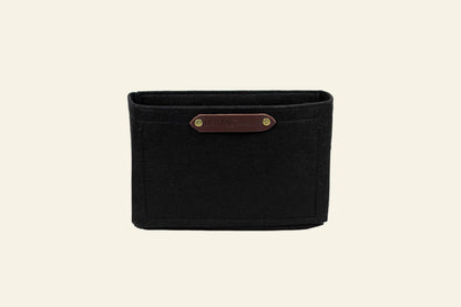 Black woven basket with a brown leather strap on a white background