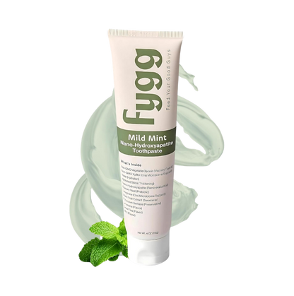 A tube of Fygg Mild Mint nano-hydroxyapatite toothpaste, featuring a pale pink and white design with green text, set against a white background with mint leaves and a mint-green toothpaste swirl graphic.