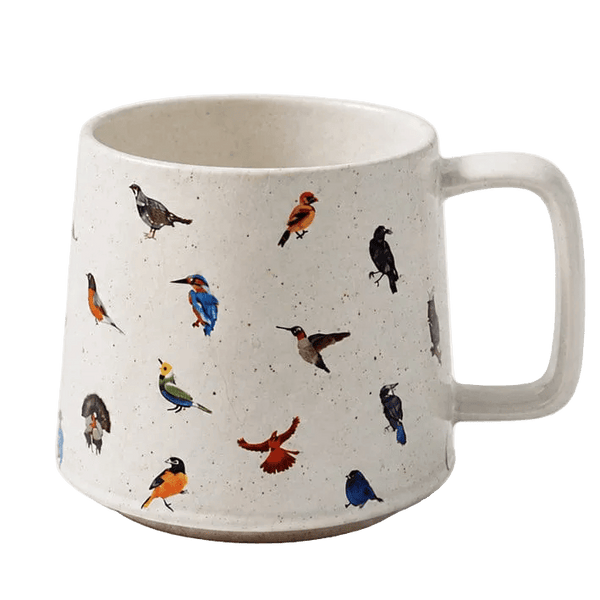 A speckled off-white ceramic mug with a handle, decorated with various colorful bird illustrations in different poses, shown against a solid green background.