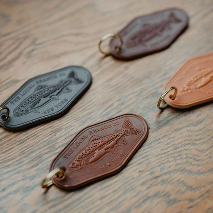Three leather keychains with fish embossing on a wooden surface