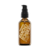 An amber glass pump bottle of Rancho Bombero Best Body Oil with a black pump dispenser and gold lettering, isolated on a white background.