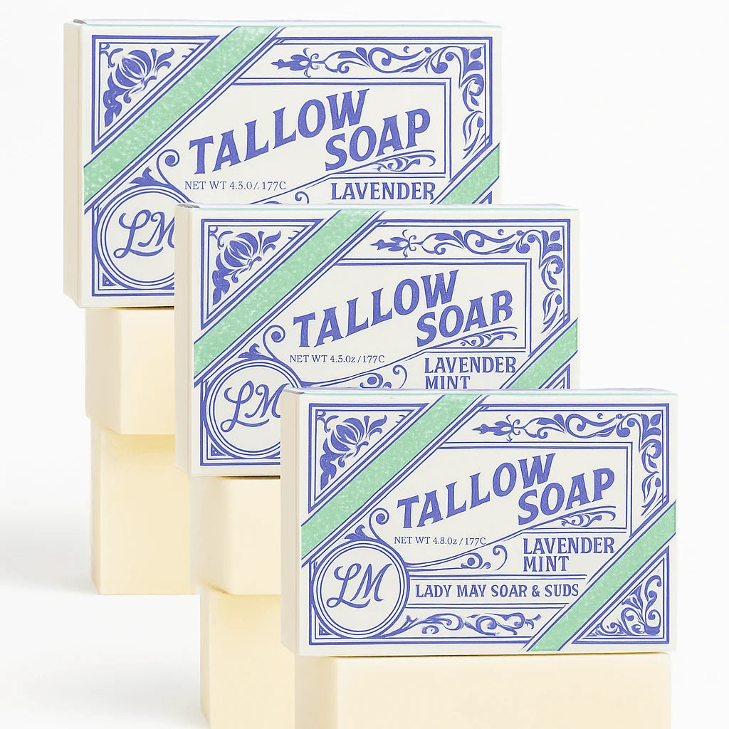 Three bars of Tallow Soap stacked diagonally, showing the lavender mint scent. The bars are cream-colored, and the packaging features a white label with blue ornate borders and a diagonal mint green stripe.