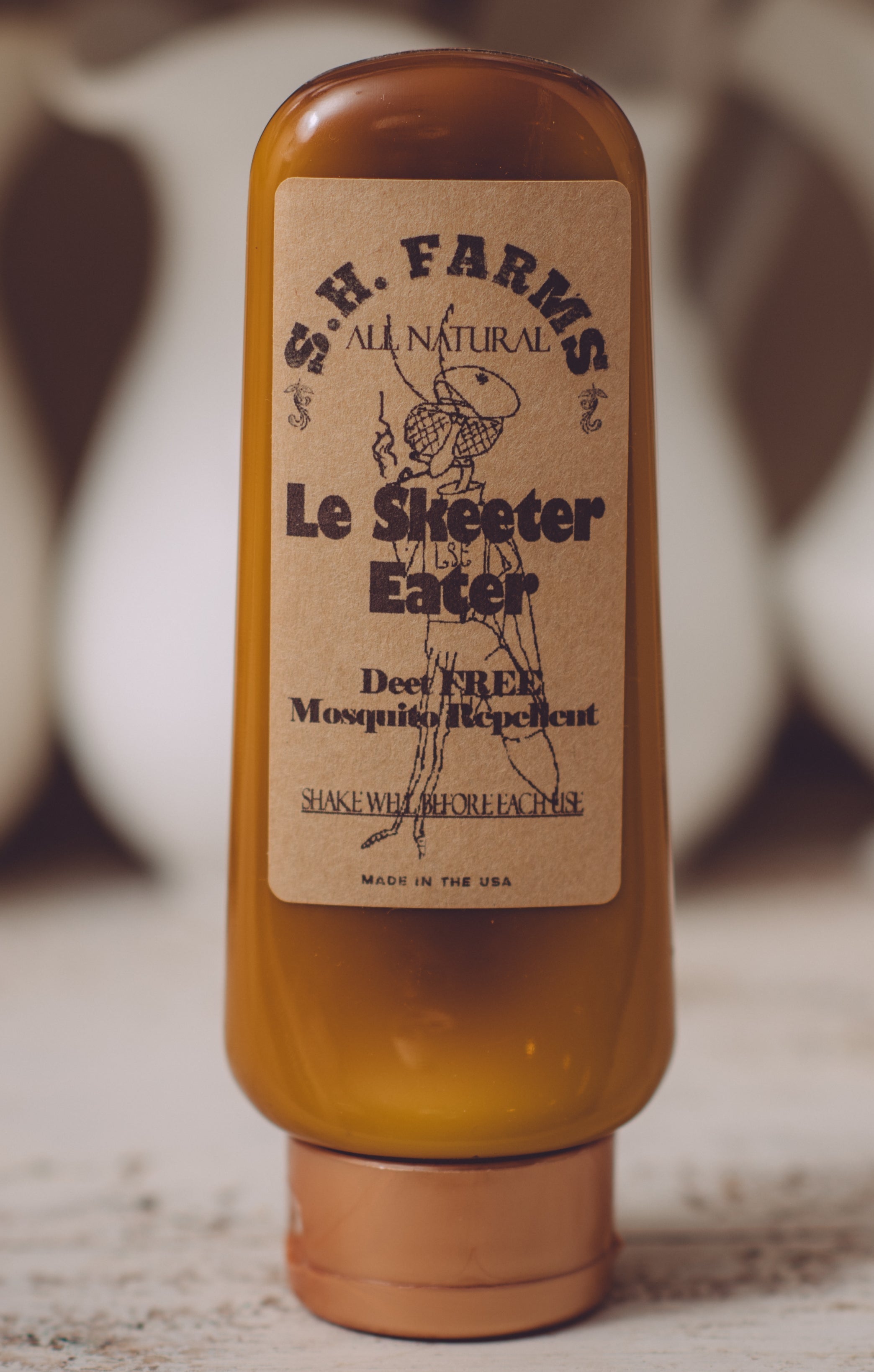 Bottle of S. H. Farms Le Skeeter Eater on a wooden surface with blurred background