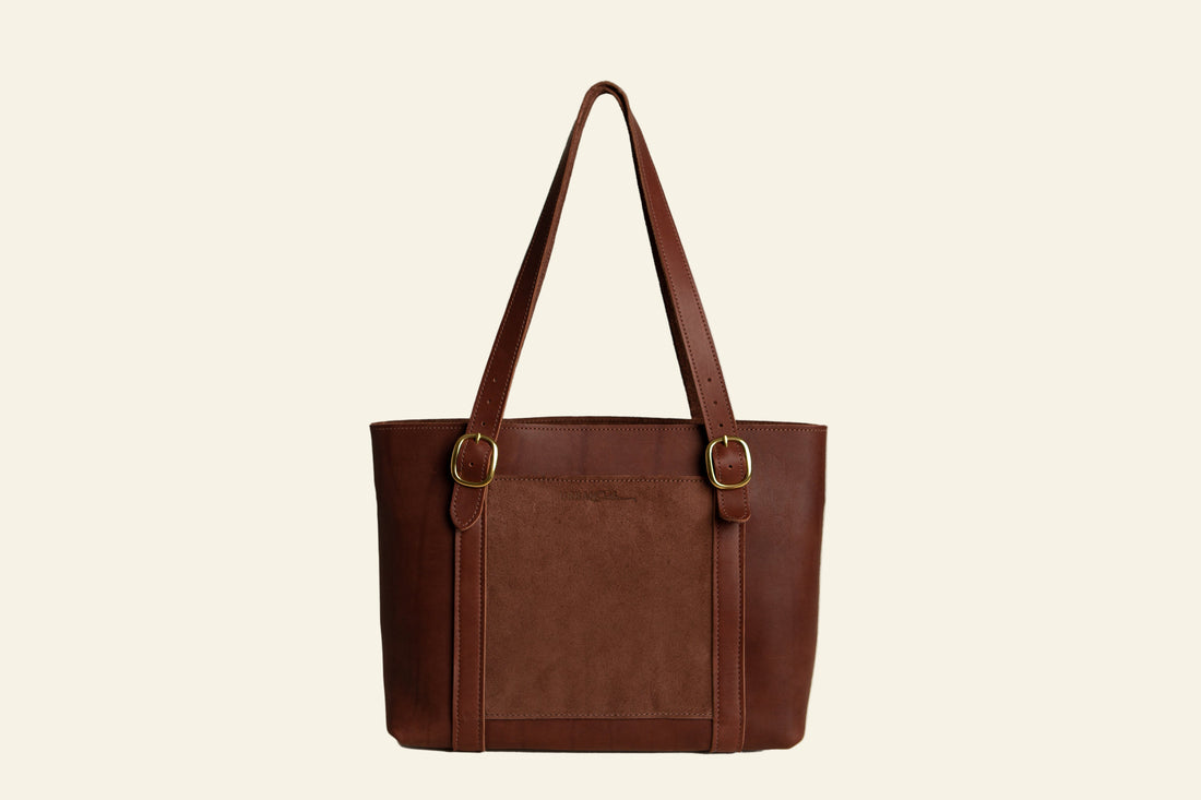 Brown leather tote bag with gold buckles on a white background