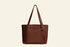 Brown leather tote bag with gold buckles on a white background