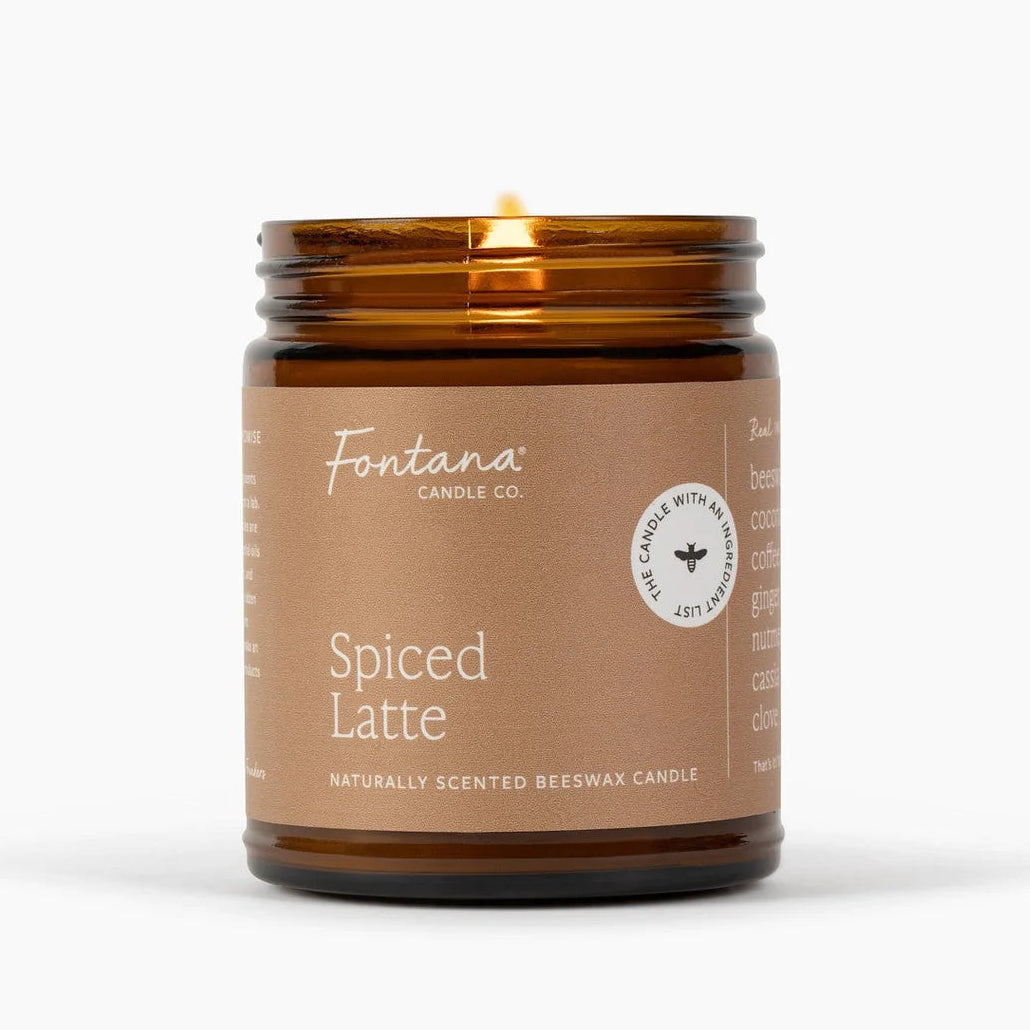 A lit Fontana Candle Co. Spiced Latte candle in an amber glass jar with a brown paper label, set against a clean white background.