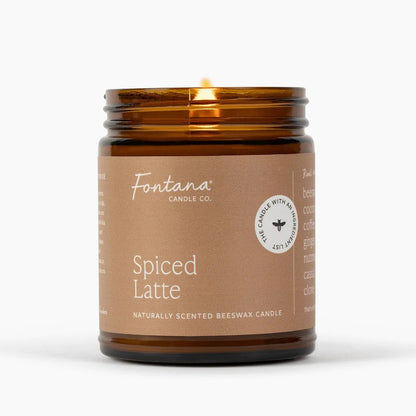 A lit Fontana Candle Co. Spiced Latte candle in an amber glass jar with a brown paper label, set against a clean white background.