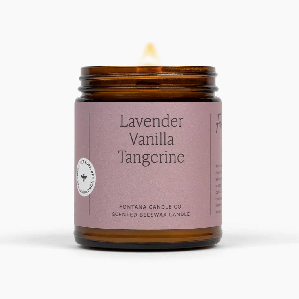 Lavender Vanilla Tangerine candle in an amber jar with a purple label on a white background