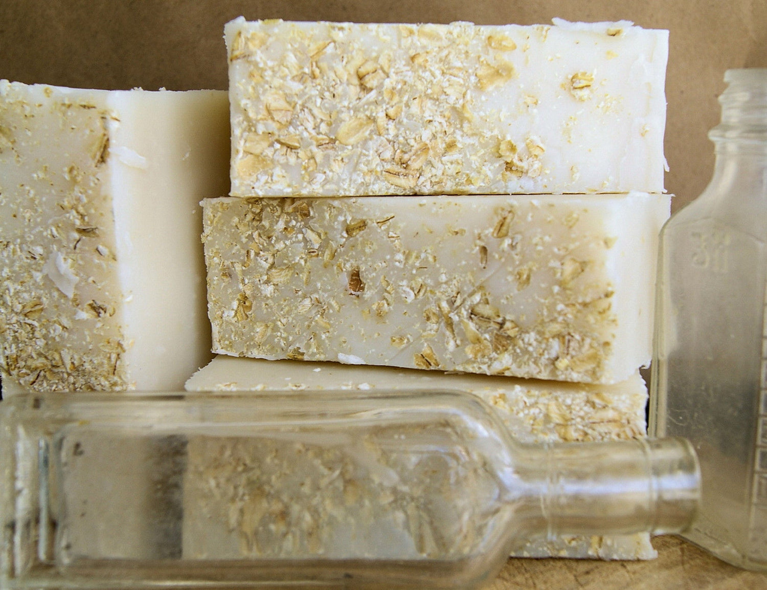 Three bars of soap with oatmeal pieces on a reflective surface